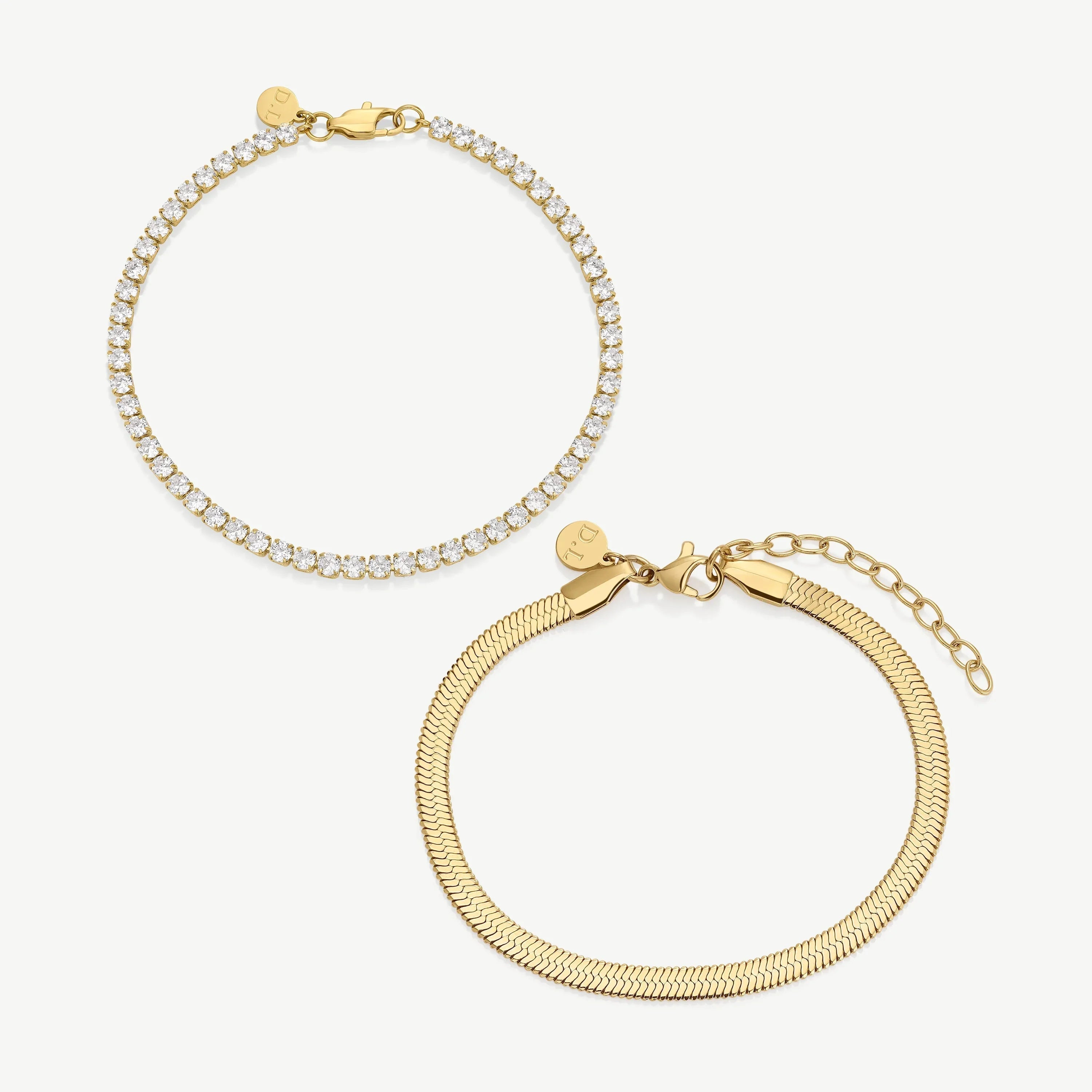 Two gold bracelets on white background, one with sparkling clear stones, one with smooth snake chain