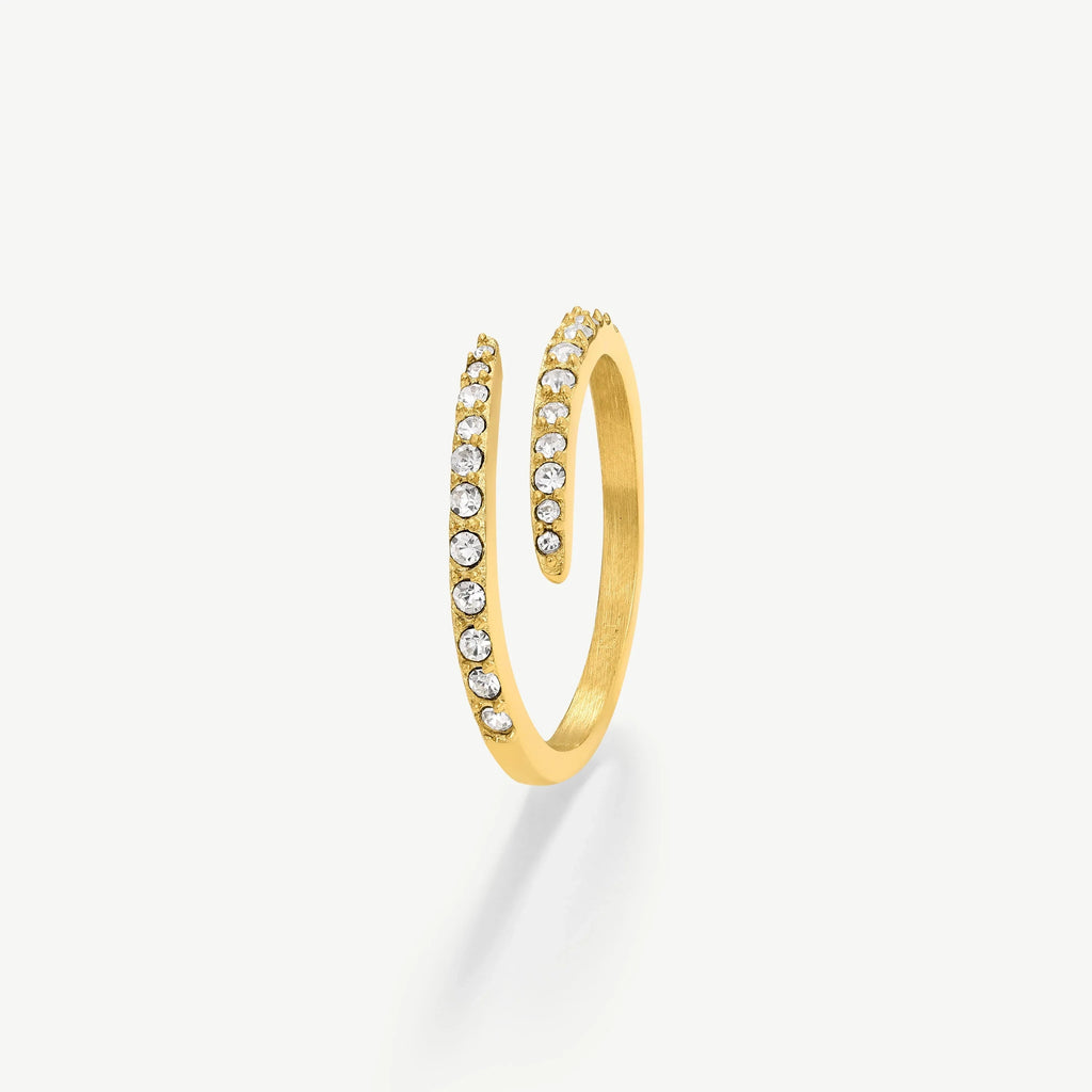 Gold spiral ring adorned with clear sparkling gemstones on a white background