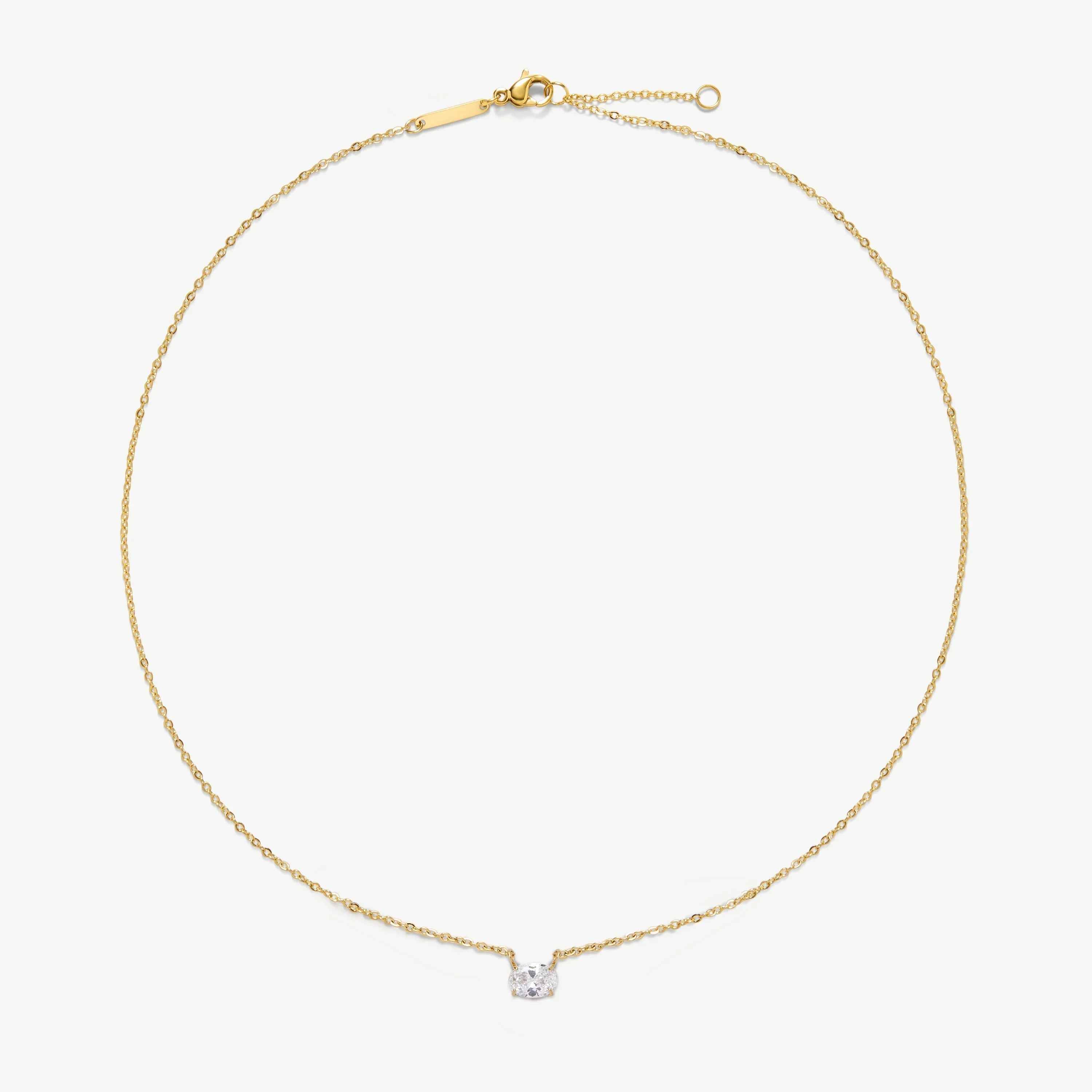 Delicate gold chain necklace with a small clear gemstone pendant on white background