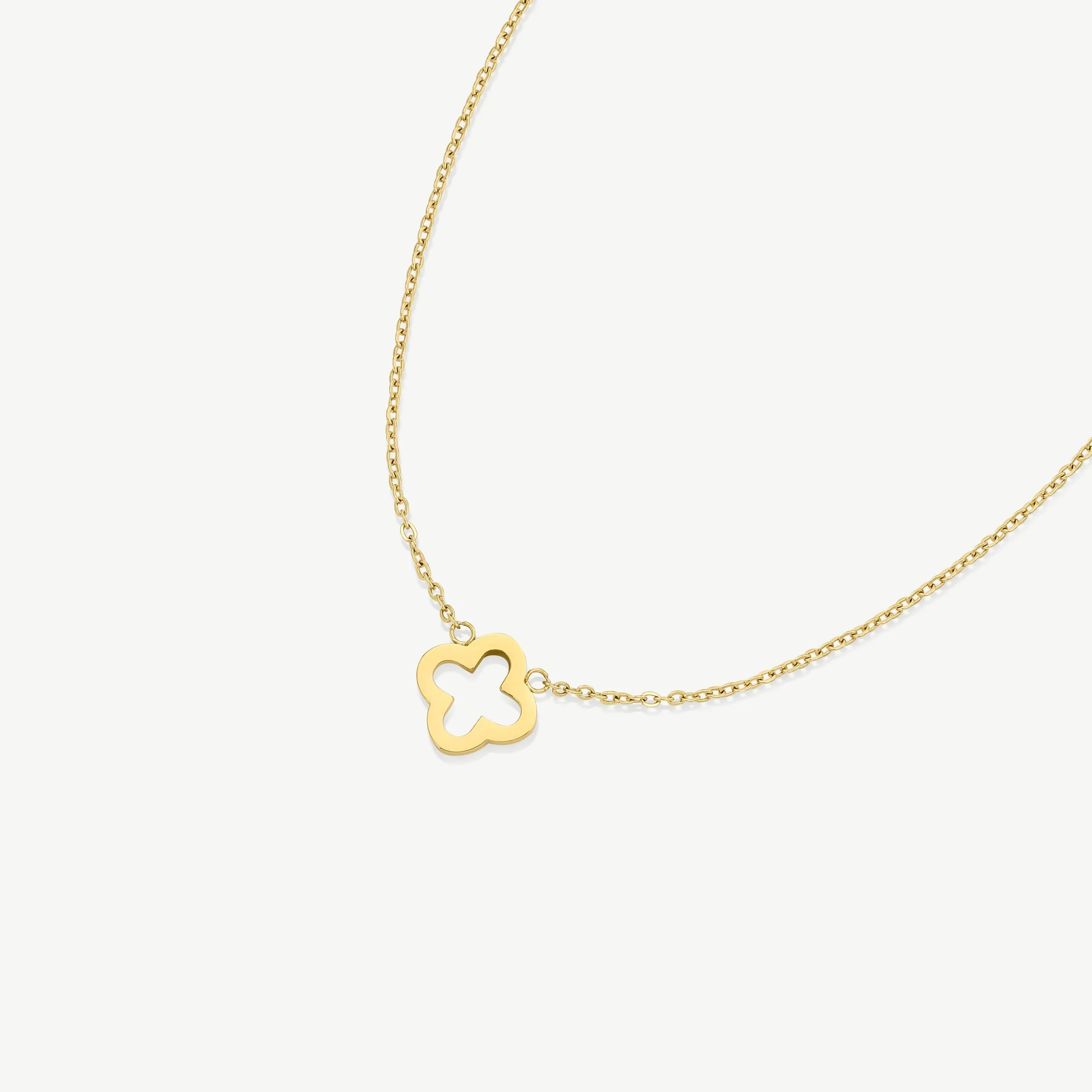 Gold chain necklace with small quatrefoil pendant on white background