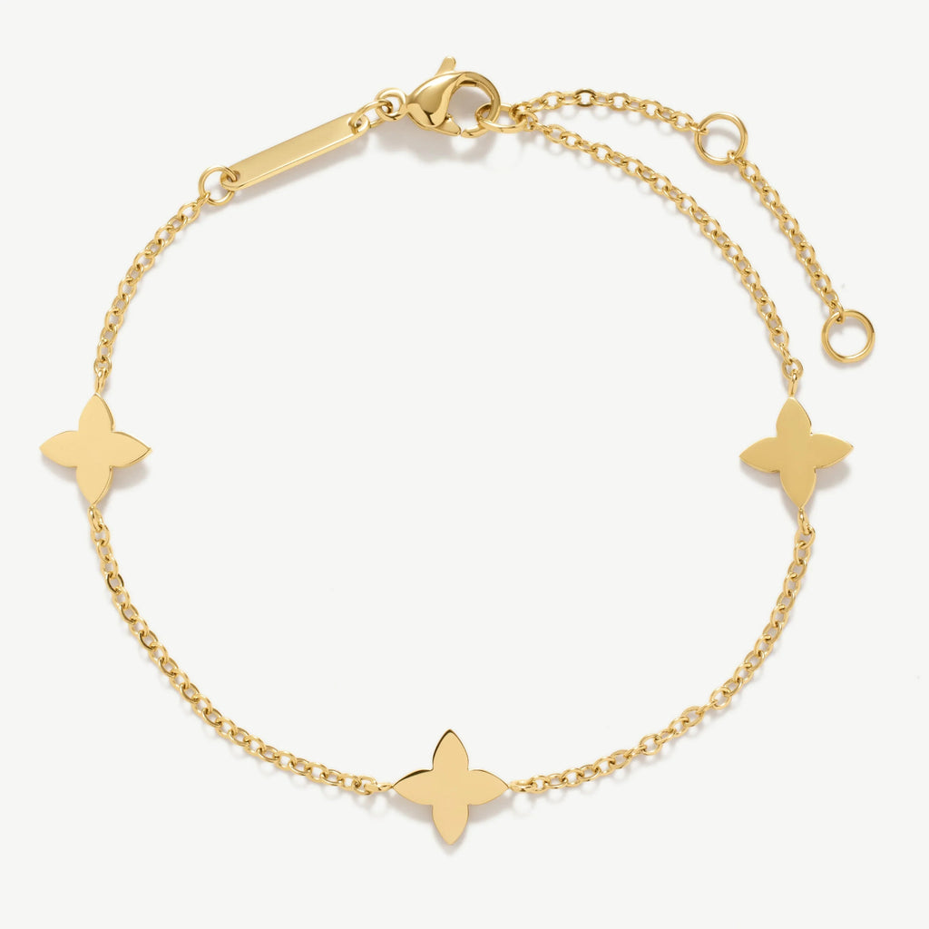 Gold chain bracelet with three flower-shaped charms and lobster clasp on white background