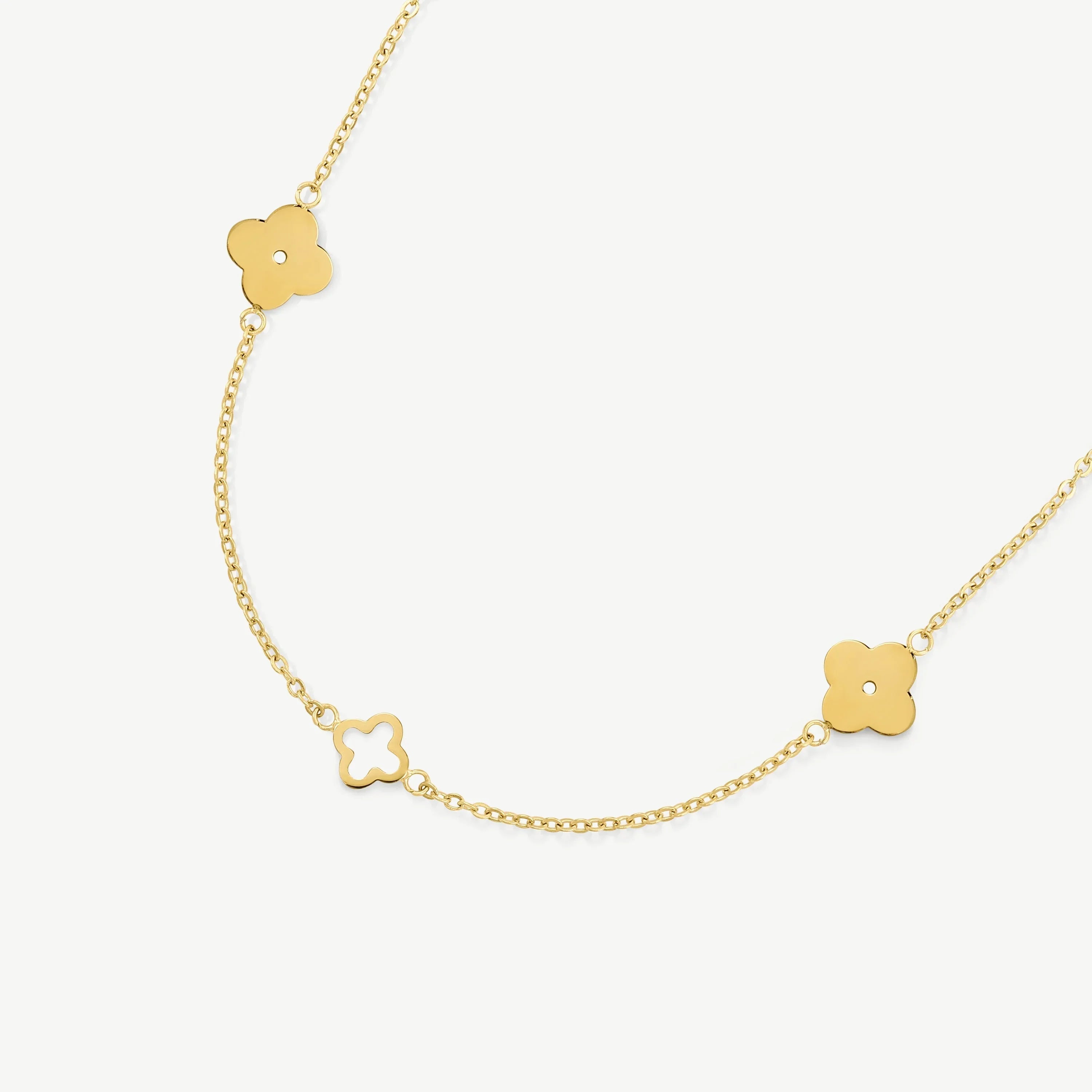 Delicate gold chain necklace with clover-shaped pendants on white background