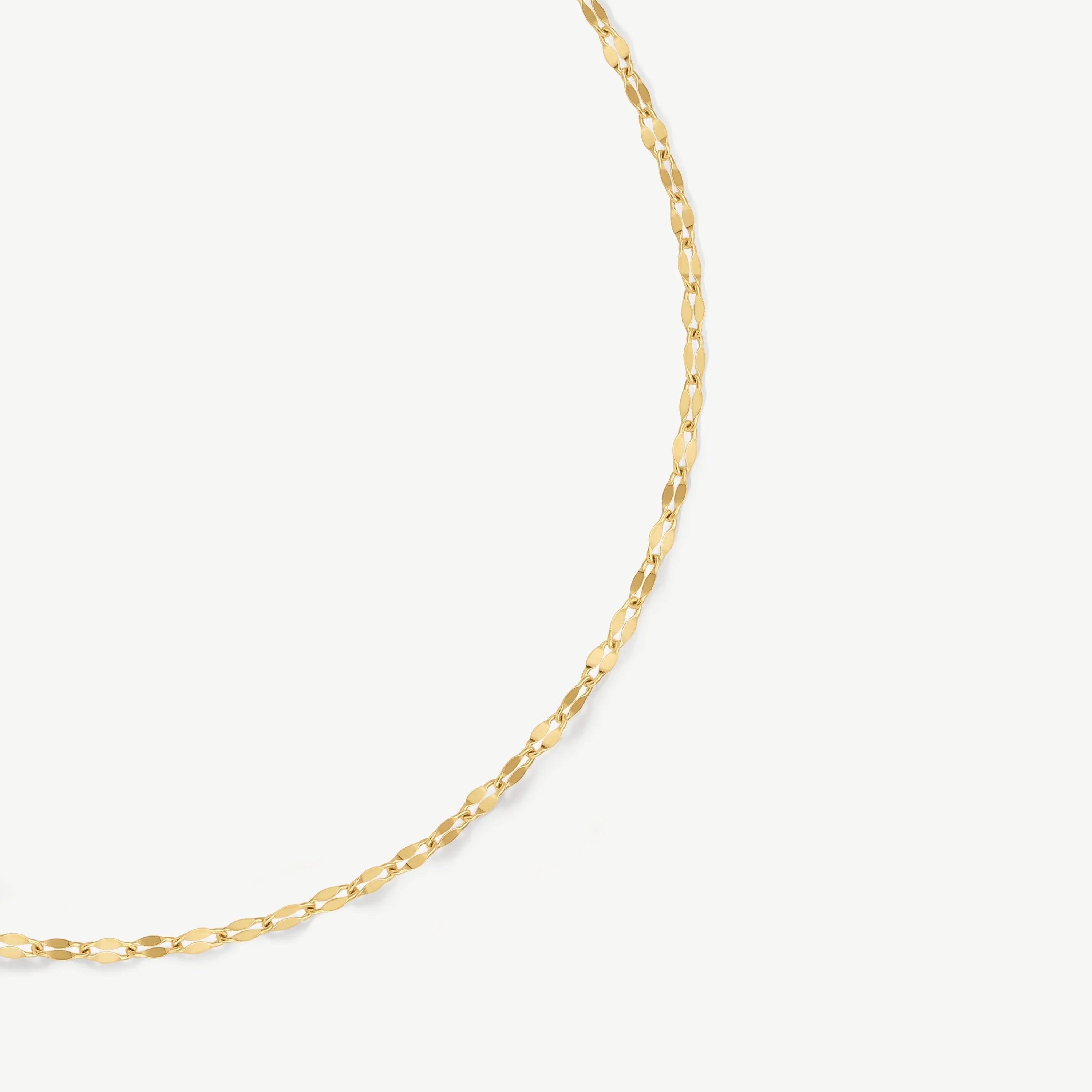 Delicate gold chain necklace with elongated oval links on white background
