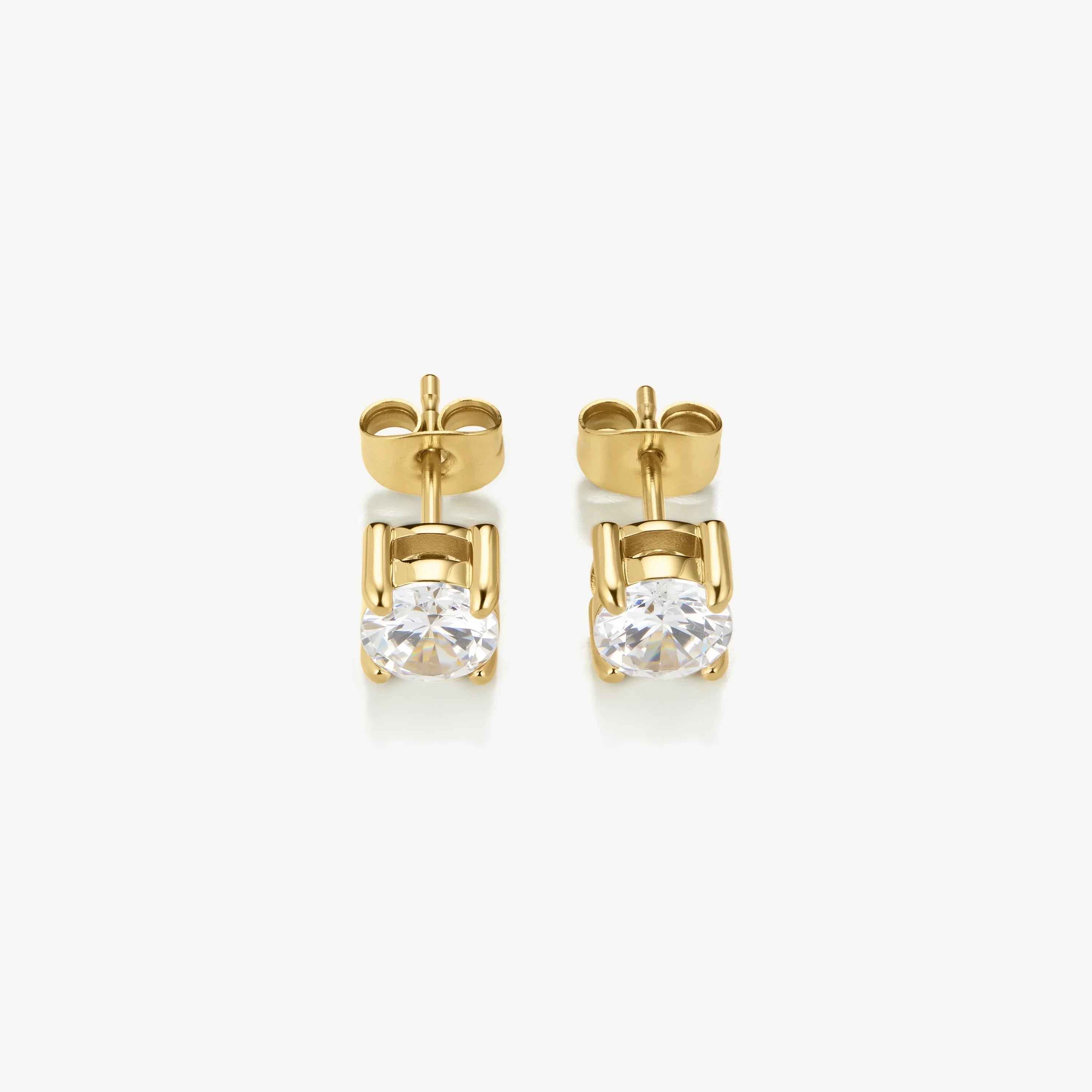 Pair of gold stud earrings with round clear gemstones on white background