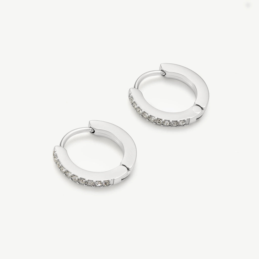 Silver hoop earrings with small clear crystals on a white background