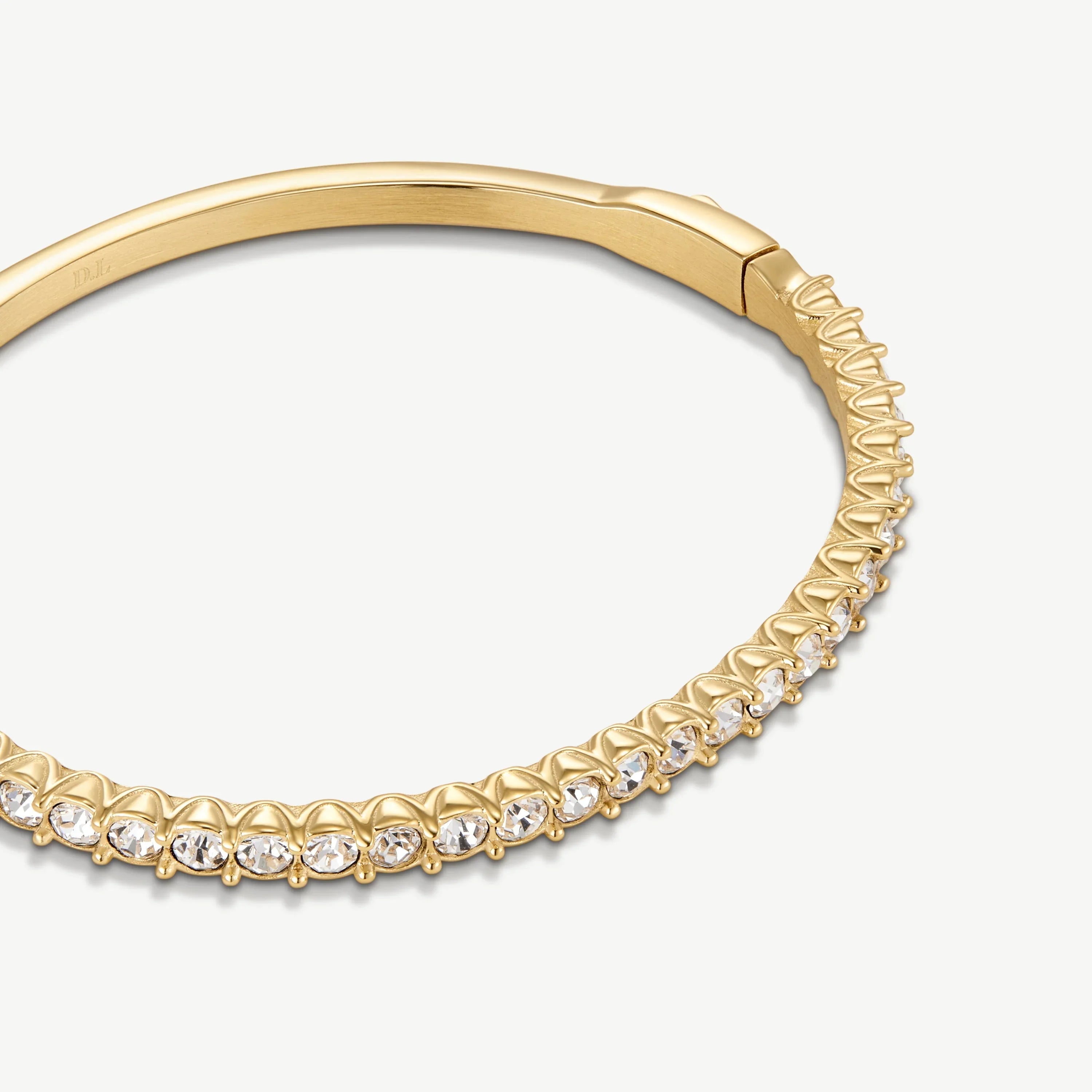 Elegant gold bangle bracelet with clear round gemstones set in a zigzag pattern