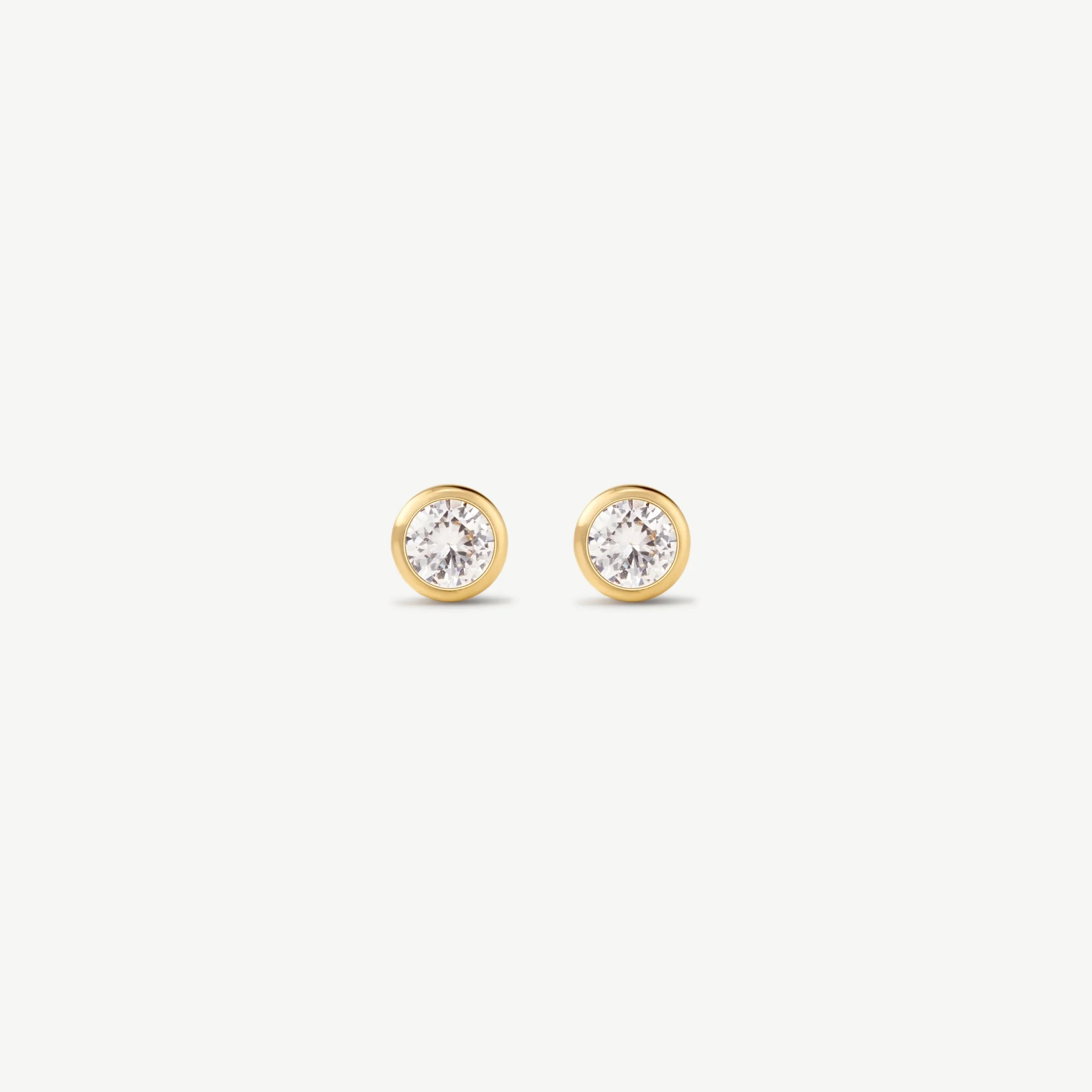 Pair of gold bezel-set diamond stud earrings on white background