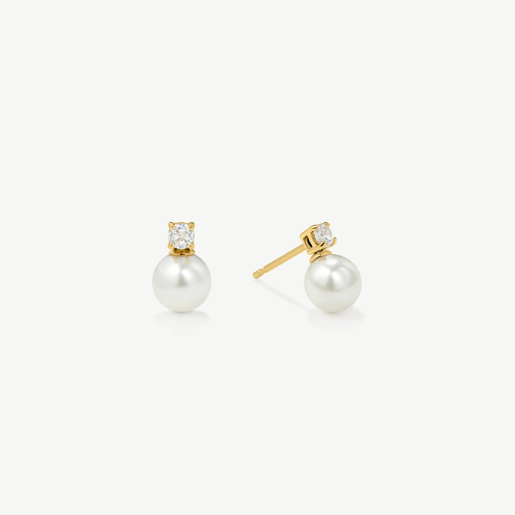 Elegant gold stud earrings with white pearls and small clear gemstones on white background
